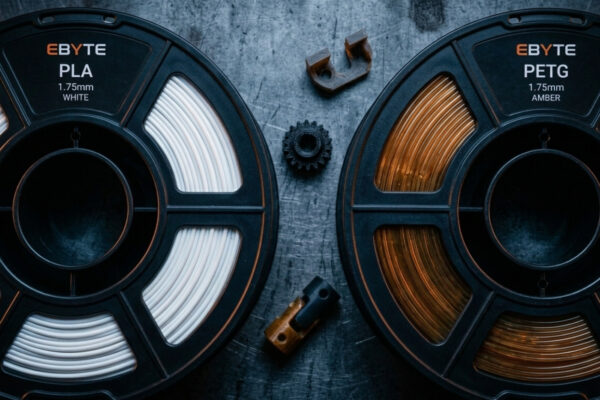 PLA vs PETG: dois carretéis de filamento para impressão 3D de peças mecânicas sobre bancada industrial